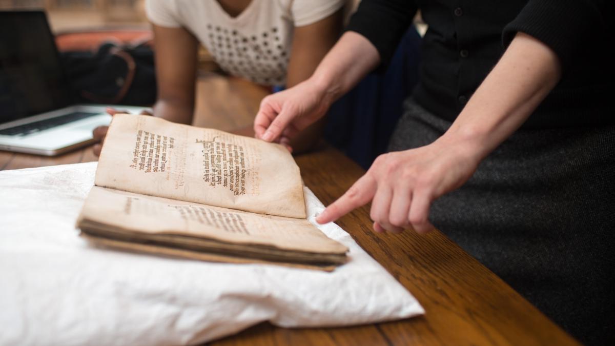 Student handles age-worn book in the Coates Library Special Collections and Archives.
